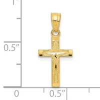 A gold crucifix pendant with textured surface and small crossbeam details, shown next to a ruler indicating approximately one inch in height.