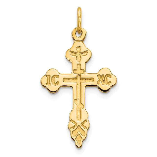 Gold cross pendant with ornate flared ends and decorative flourishes at the bottom, featuring initials on the horizontal arms and a loop at the top for hanging.