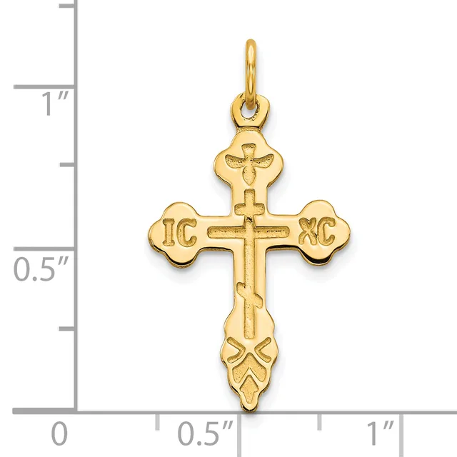 Gold-toned cross pendant with ornate ends featuring "IC XC" initials and decorative flourishes, shown against a measurement scale.