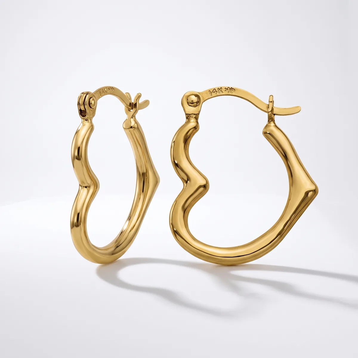 A pair of gold twisted hoop earrings with hinged closures, displayed against a white background with subtle shadows.