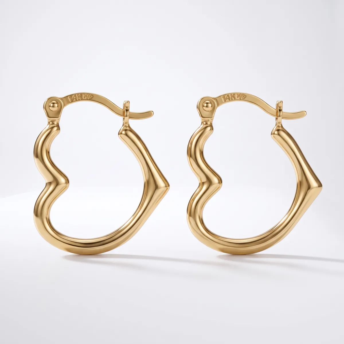 A pair of gold-toned hoop earrings with a wavy, curved design and hinged posts, displayed against a white background.