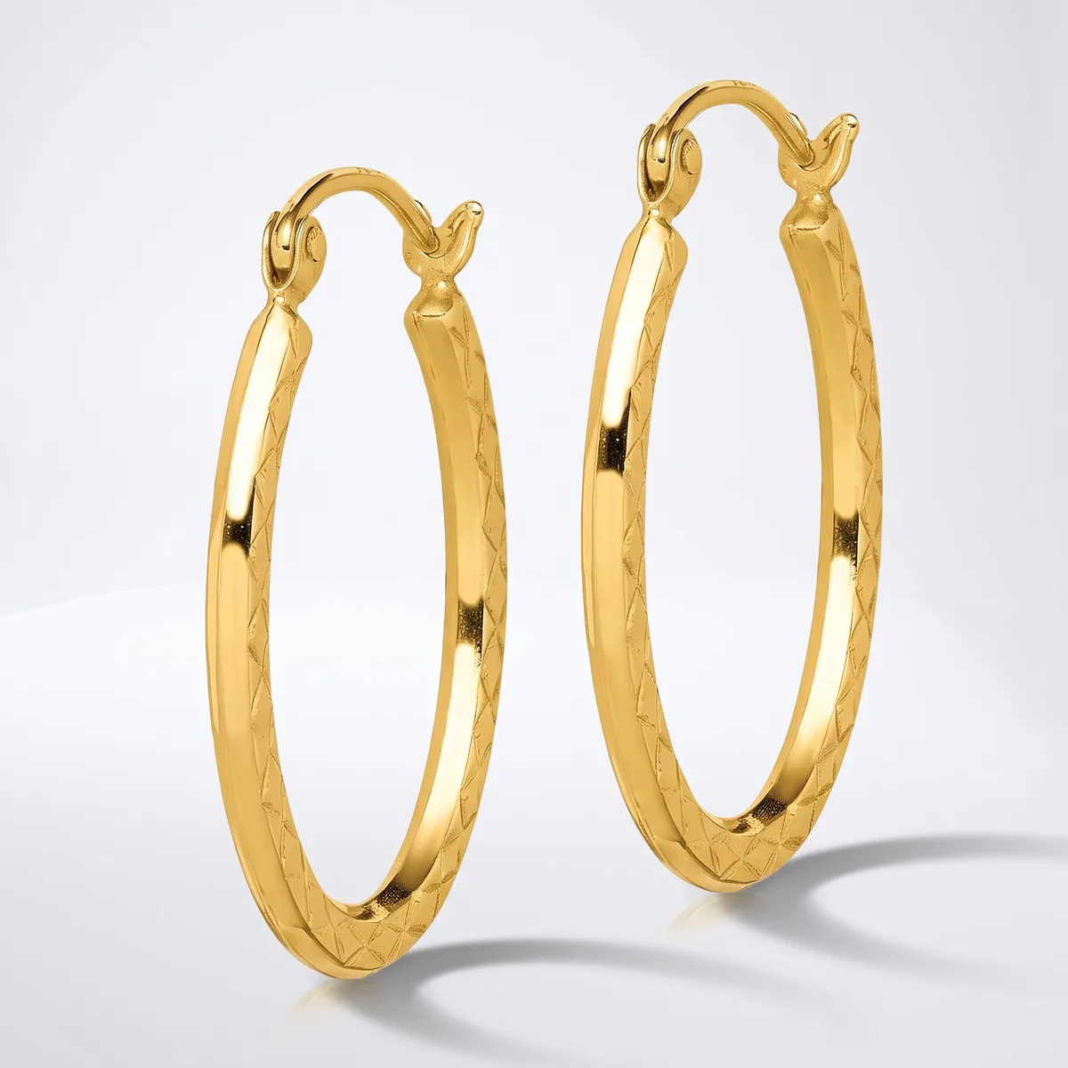 A pair of gold hoop earrings with textured surfaces and hook clasps, displayed against a white background.