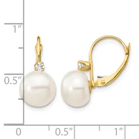 A pair of gold lever-back earrings featuring white pearl drops with small diamond accents, displayed next to a measurement scale.
