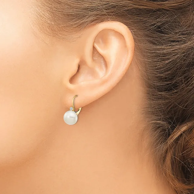 A woman wearing a white pearl drop earring with a curved silver hook, shown from the side profile of her ear and neck.