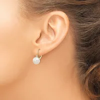 A woman wearing a white pearl drop earring with a curved silver hook, shown from the side profile of her ear and neck.