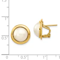 A pair of gold-toned stud earrings with white pearl centers and omega backs, displayed next to a ruler showing approximately one inch in diameter.