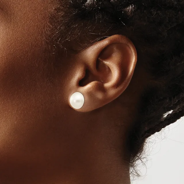 A person with dark skin and black hair wears a white pearl stud earring in their earlobe, shown in profile against a neutral background.