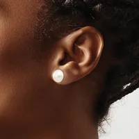 A person with dark skin and black hair wears a white pearl stud earring in their earlobe, shown in profile against a neutral background.