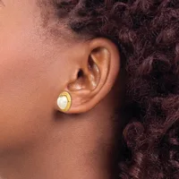 A person wearing a gold-toned earring with a white stone or pearl in the center, shown from the side profile against their ear.