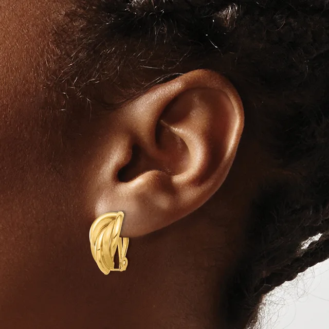 Gold-toned chunky ridged hoop earrings worn on the earlobe of a person with brown skin and dark hair.