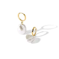 Two gold hoop earrings with white pearl charms hanging from them, displayed on a white surface with shadows.