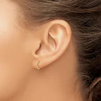 A person wearing a small curved gold crescent moon earring in their earlobe, shown in close-up profile view.