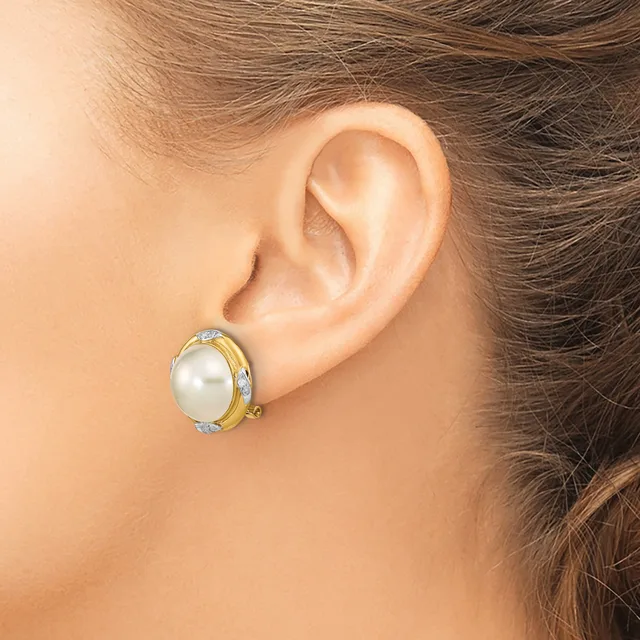 A woman wearing a two-tone earring with a white pearl center surrounded by small diamonds in a gold and silver setting, shown from the side view of her ear.