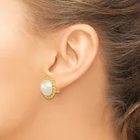 A close-up side view of a person's ear wearing a gold-toned oval earring with a white pearl center and textured twisted metal frame.