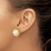 A woman wearing a gold-toned earring with a textured oval frame holding a white pearl stud, shown from the side profile of her ear and neck.