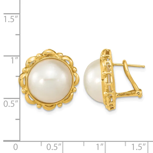 Pair of gold-toned clip earrings with white pearl centers surrounded by ornate scalloped bezels, shown next to a measurement ruler.