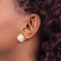 A person wearing a gold-toned stud earring with a round white pearl or moonstone cabochon, shown from the side profile.