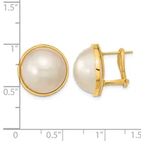 Pair of gold-toned stud earrings with large round white pearl centers in bezel settings, shown front and side view against a measurement scale.