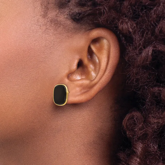 A person wearing a gold-rimmed oval earring with a black center stone in their pierced earlobe, shown in profile.