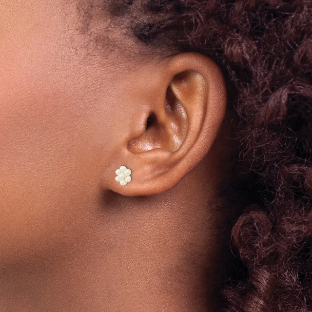 A person wearing a small white flower-shaped stud earring in their earlobe, shown in profile view.