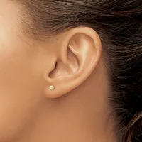 A close-up view of a person's ear wearing a single small pearl stud earring in the lobe.