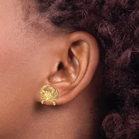 A person wearing a gold crab-shaped stud earring in their earlobe, shown in profile against their neck and dark curly hair.