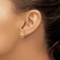 A person wearing a small gold-colored teddy bear charm earring in their pierced earlobe, shown in profile.