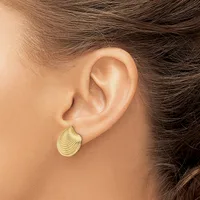 A person wearing a gold teardrop-shaped earring with textured linear surface details, shown from the side view of their ear and neck.