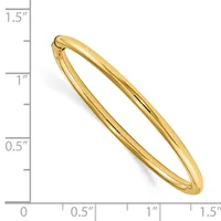 A polished gold-colored bangle bracelet with a hinged clasp, shown next to a ruler indicating its size is approximately 1.25 inches in width.