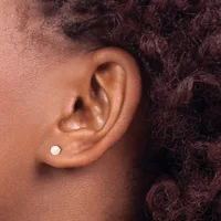 A close-up side view of a person's ear wearing a small white pearl stud earring in the lower lobe.