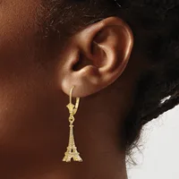 A person wearing a gold Eiffel Tower charm earring that hangs from a gold lever-back hook on their earlobe.