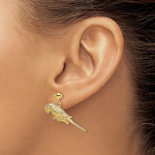 A gold parrot charm earring hangs from a gold ball post on a person's earlobe.