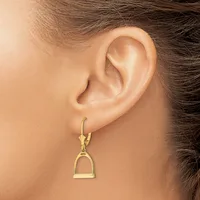 A gold stirrup-shaped dangle earring with a leverback clasp shown worn on a person's earlobe.