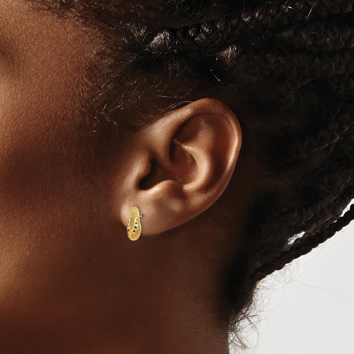 A woman wearing a small gold hoop earring with a textured surface, shown from the side view of her ear and neck.