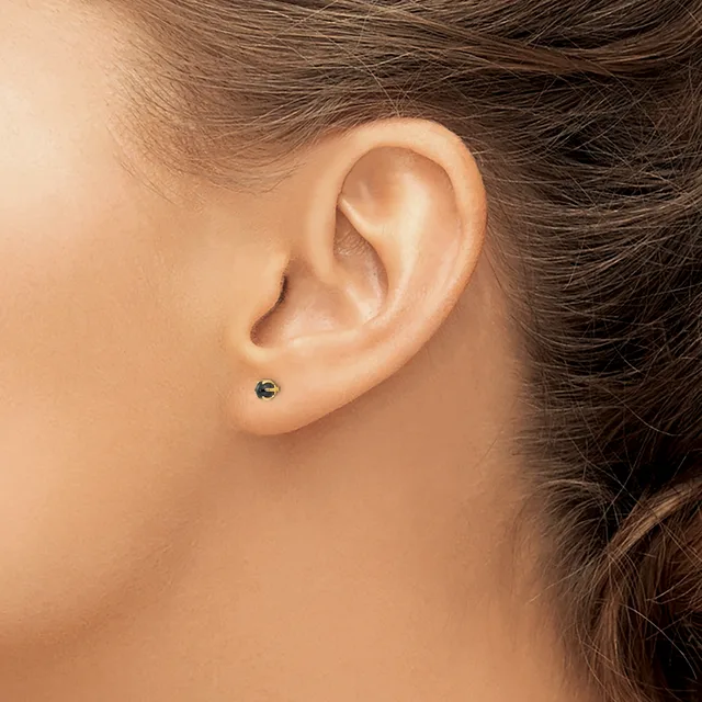 A person with brown hair wearing a small dark gemstone stud earring in their earlobe, shown in profile view.