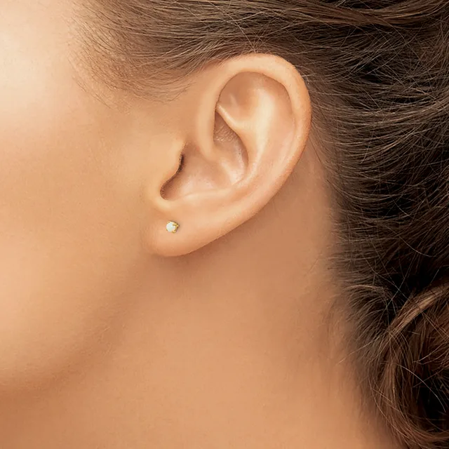 A person's ear wearing a small diamond stud earring in the lower lobe, shown in profile against a neutral background.