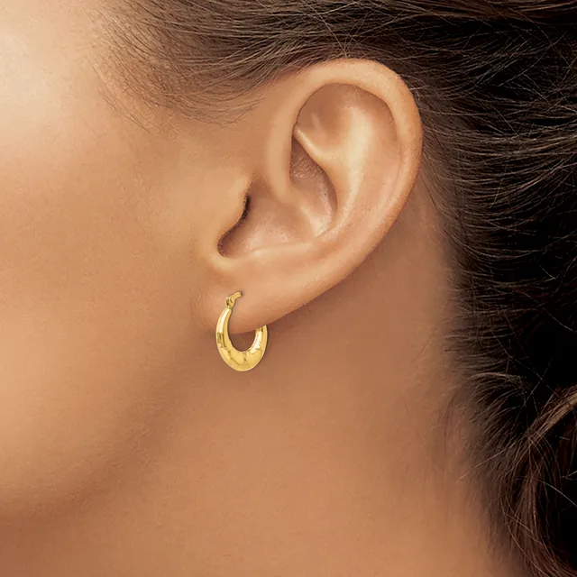A person wearing a small textured gold hoop earring in their earlobe, shown in profile view against their neck and shoulder.