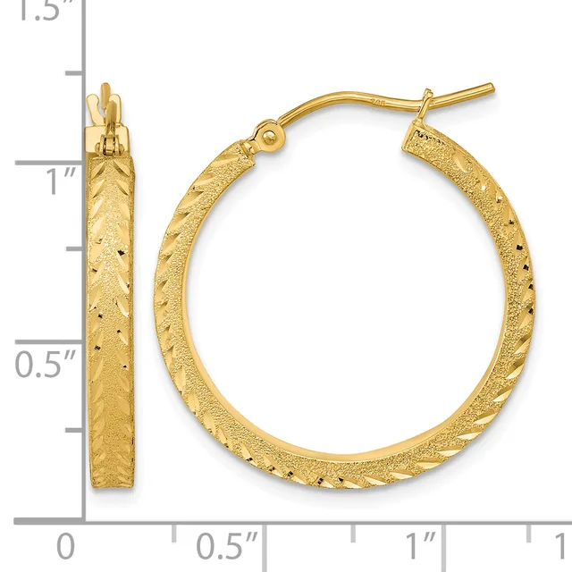 A pair of gold textured hoop earrings with a hammered finish and hinged posts, shown against a measurement scale indicating approximately one inch in diameter.