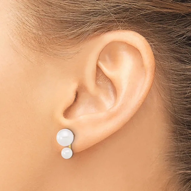 A person wearing white pearl stud earrings with a larger pearl on top and smaller pearl below on each ear, shown from the side profile.