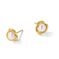 A pair of gold stud earrings, each featuring a white pearl set within a curved gold bezel with decorative scroll details on either side.