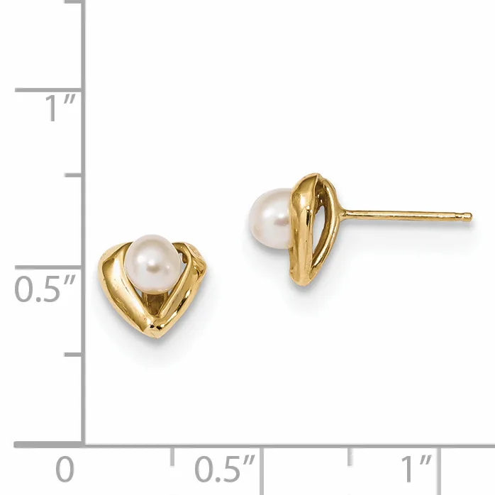 A pair of gold stud earrings with heart-shaped settings holding white pearl centers, displayed against a measurement scale.