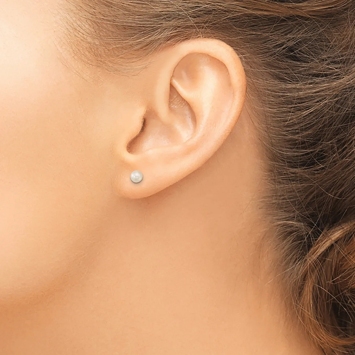 A person wearing a small pearl stud earring is shown in profile, displaying the earring in the earlobe.