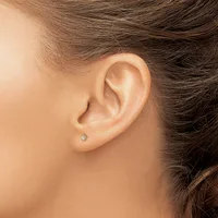 A person wearing a small round stud earring with a light blue stone in their pierced earlobe, shown in profile view.