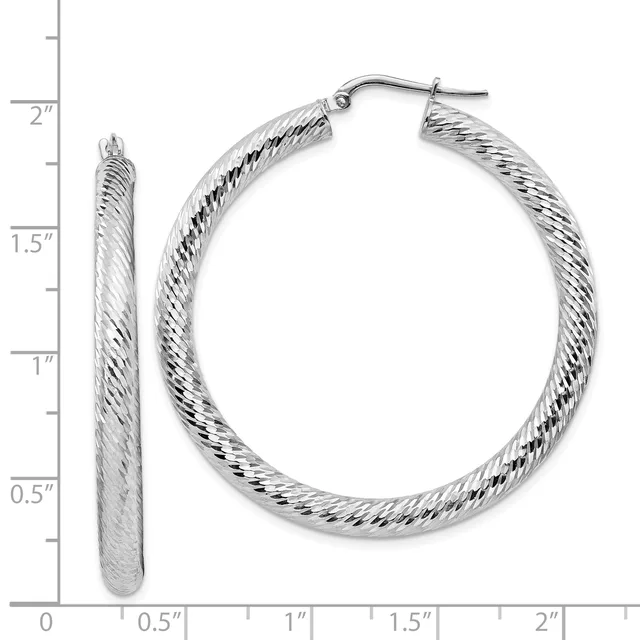 Pair of silver-toned twisted hoop earrings with post and clutch backs, displayed against a measurement ruler showing approximately 1.5 inches in diameter.