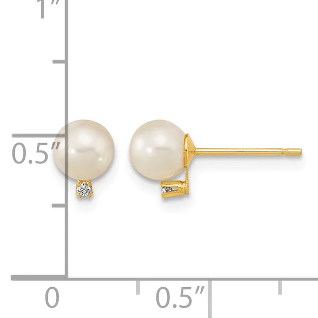 A pair of gold stud earrings featuring cream-colored pearl spheres with small diamond accents, shown next to a measurement scale.