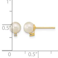 A pair of gold stud earrings featuring cream-colored pearl spheres with small diamond accents, shown next to a measurement scale.