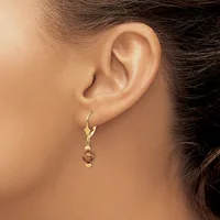 A woman wears a gold lever-back earring with a small spherical bronze or copper-colored bead suspended below a series of smaller gold beads.