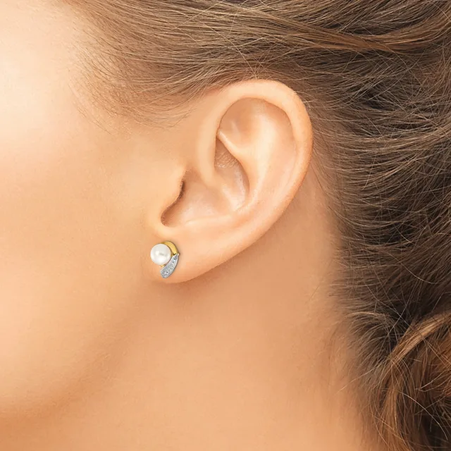 A person wearing a small stud earring with a white pearl center and diamond accents in white metal, shown in profile from the side of their face.