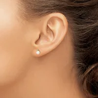 A person wearing a pearl drop earring with a diamond accent, shown from the side view of their ear and neck.