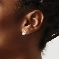 A close-up view of a person's ear wearing a small silver hoop earring with a white pearl or stone accent.
